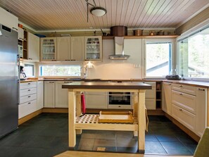 A kitchen with wooden cabinets, a central island, and a window providing natural light. - Villa kuusiranta by Interhome (Kuopio)
