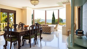 Un comedor con una mesa y sillas, un sofá y vista al mar.