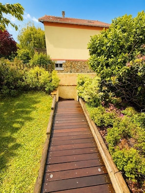 Un sentiero in legno conduce a un edificio con un muro in pietra e un tetto in tegole.