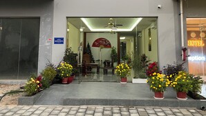 A hotel entrance with a reception desk, a Christmas tree, and potted plants. - Namca Hotel  (Phu Quoc)