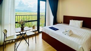 A hotel room with a bed, a small table with chairs, a balcony with a view, and a vase with flowers. - Namca Hotel  (Phu Quoc)