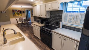 A kitchen with white cabinets, a black stove, and a window with shutters. - The Cunningham (Salina)