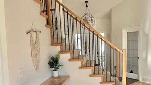 Un escalier avec des marches en bois et des rampes en métal, un banc en bois, une plante en pot et une décoration murale en macramé.