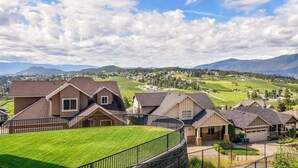 Un quartier résidentiel avec des maisons, une pelouse bien entretenue et un paysage montagneux en arrière-plan.