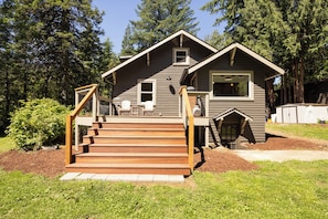 A two-story cabin with a wooden deck, a small porch, and a garage.