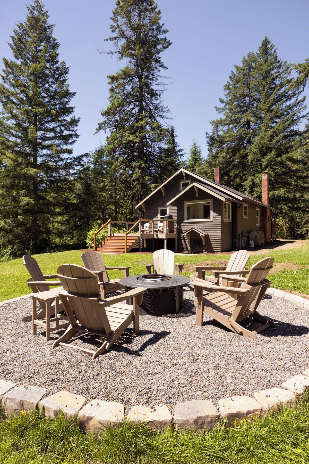 Un chalet doté d’une terrasse, d’un foyer extérieur et de fauteuils Adirondack.