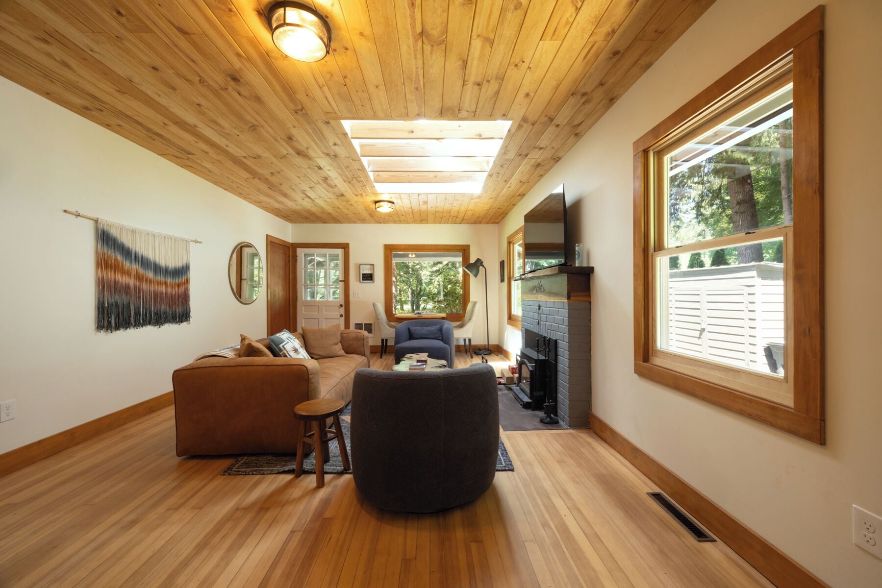 Un salon chaleureux avec un plancher en bois, une cheminée et de grandes fenêtres.