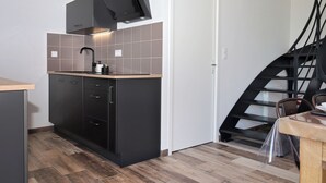 Una cocina compacta con horno integrado, lavamanos y encimera de madera.