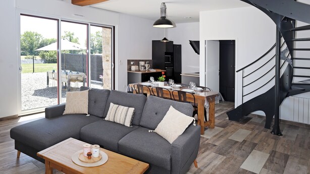 Una sala de estar moderna con sofá, mesa de comedor y escalera.