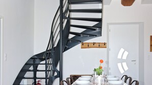 Un comedor con escalera espiral, una mesa de madera y sillas.