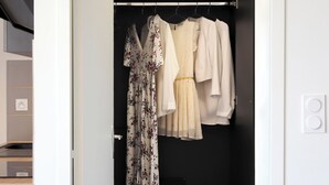 Un armario vestidor con ropa colgada, un banco y una puerta con manija.