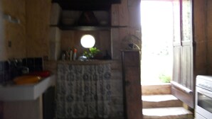 Een landelijke keuken met een stenen muur, een houten deur en een raam.