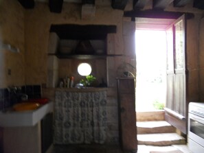 Eine rustikale Küche mit Steinwand, Holztür und Fenster.