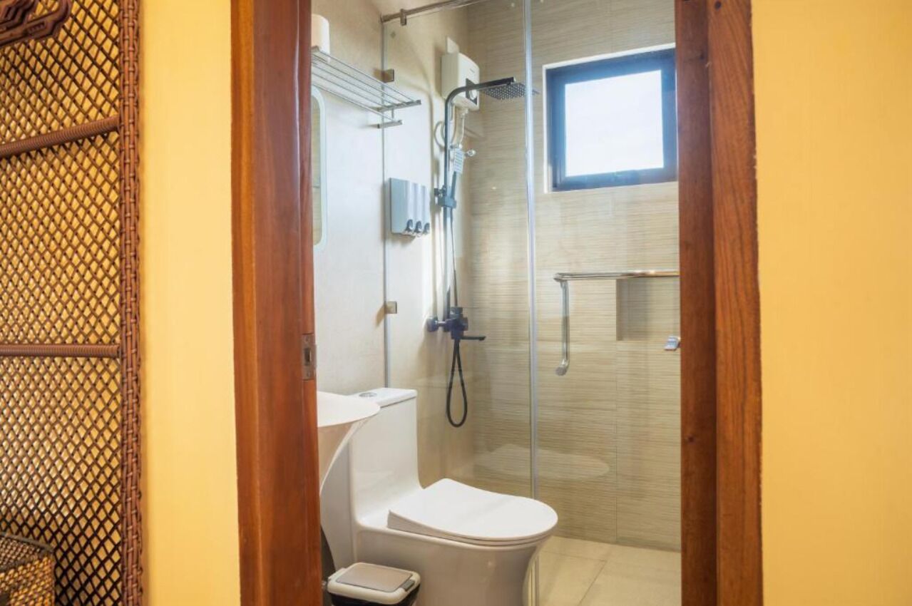 A compact bathroom with a glass shower enclosure, a white toilet, and a small window.