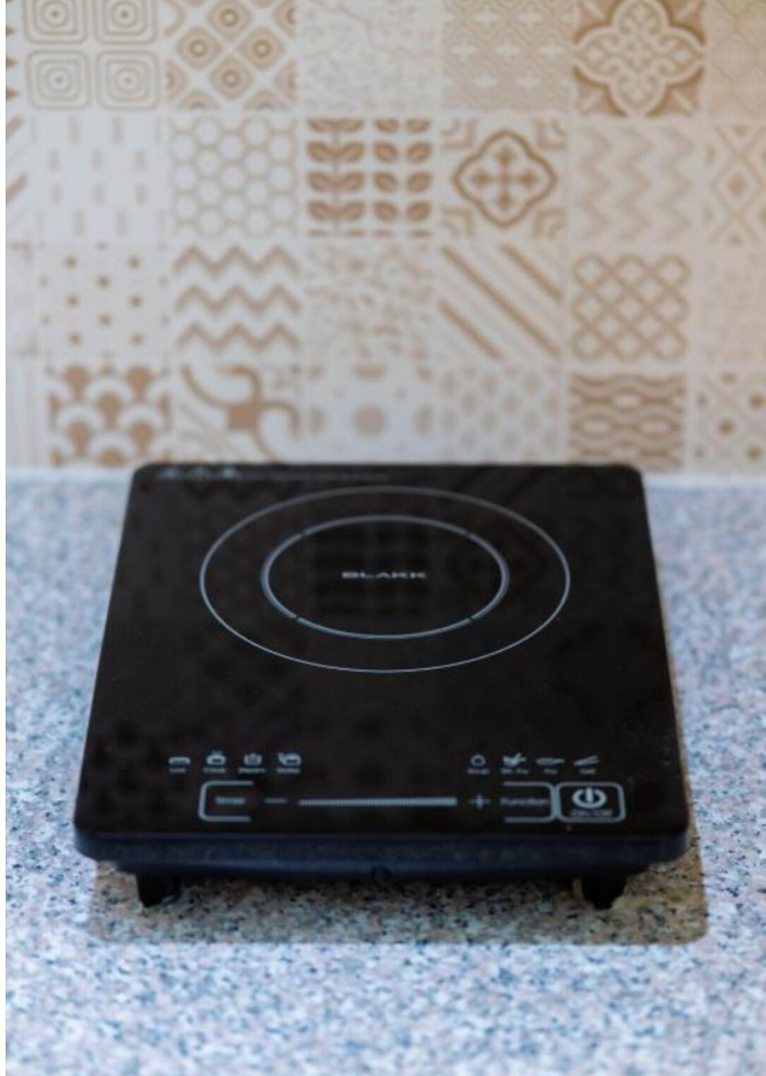 Un calentador portátil negro con un panel de control sobre una encimera de granito.