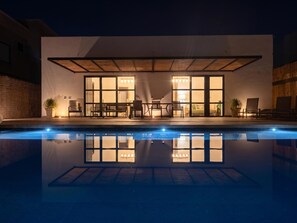 A modern building with a pool, large windows, and outdoor seating.