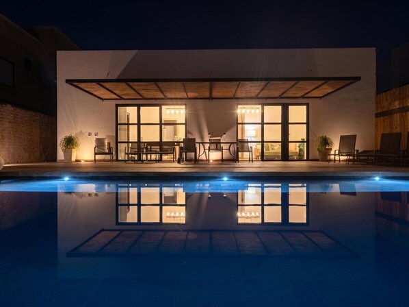 A modern building with a pool, large windows, and outdoor seating.