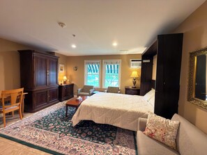 Ein Hotelzimmer mit einem Bett, einer Couch, einem Schreibtisch, einem Stuhl, einem Schrank und einem großen Fenster.