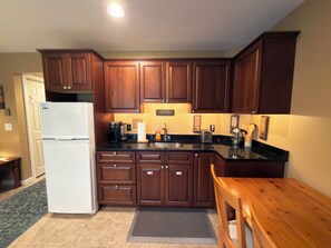 Eine Küche mit Holzausbau, einem weißen Kühlschrank, einer Spüle und einem Holztisch.
