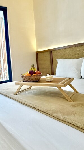 Ein Bett mit einem Holztischchen, einem Korbfruchtkorb und einem weißen Dekorationsobjekt.