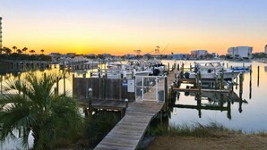A marina with boats docked, a wooden pier, and a calm water body reflecting the sky. - Sandpiper Cove 8239 Updated Condo In Destin, FL  3-minute walk to the beach! (Destin)