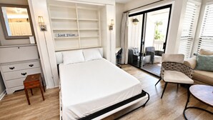A bedroom with a bed, a nightstand, a chair, a sofa, a desk, and a sliding glass door leading to a balcony. - Sandpiper Cove 8239 Updated Condo In Destin, FL  3-minute walk to the beach! (Destin)