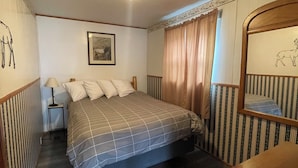 A bedroom with a bed, bedside table, lamp, and a mirror with a deer design. - Lone Pine Cabins  (Grand Lake)