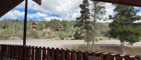 Una terraza de madera con vista a un albergue de montaña y una carretera.