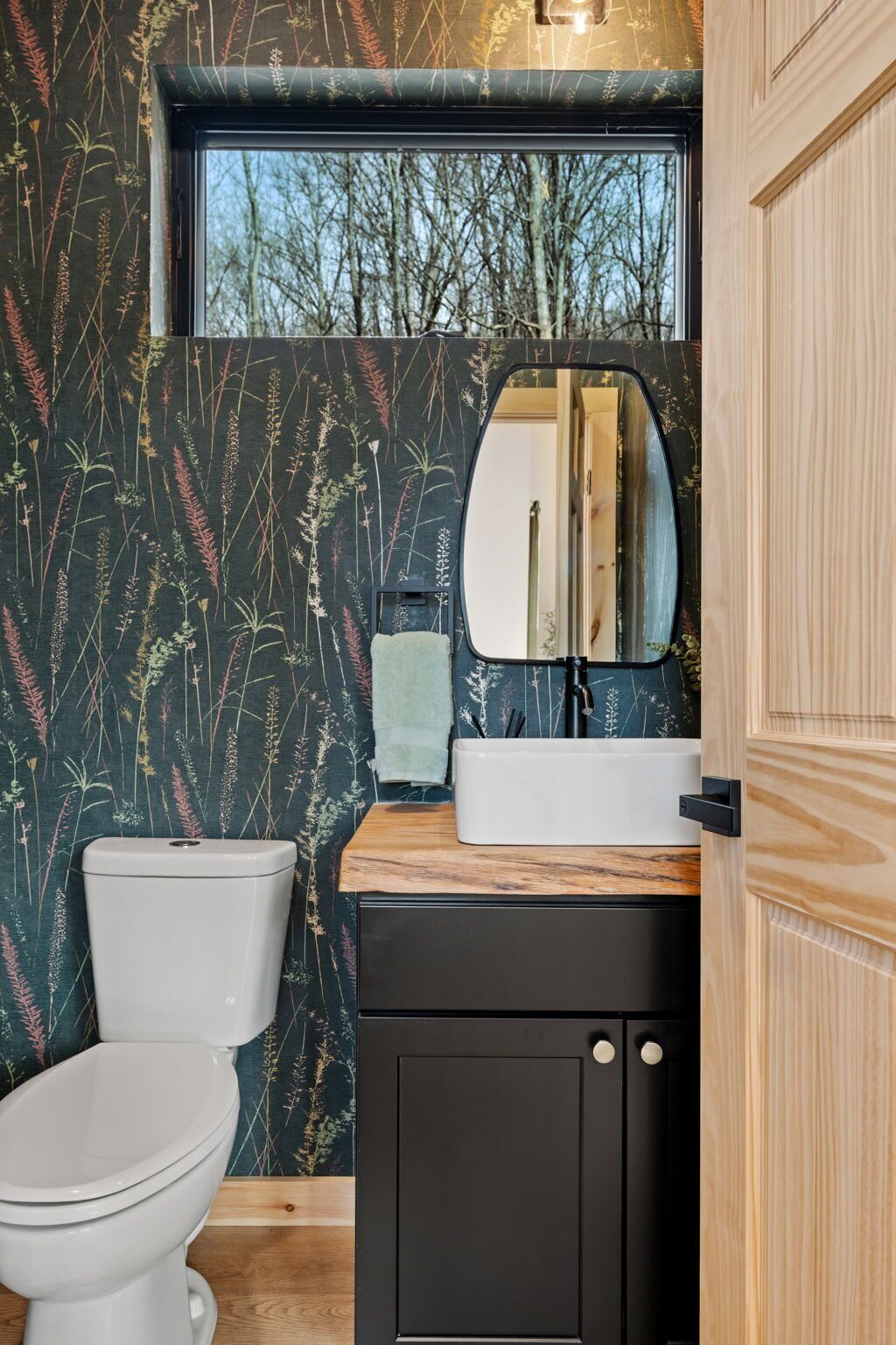 A bathroom with a toilet, a sink with a mirror, and a window above the sink.