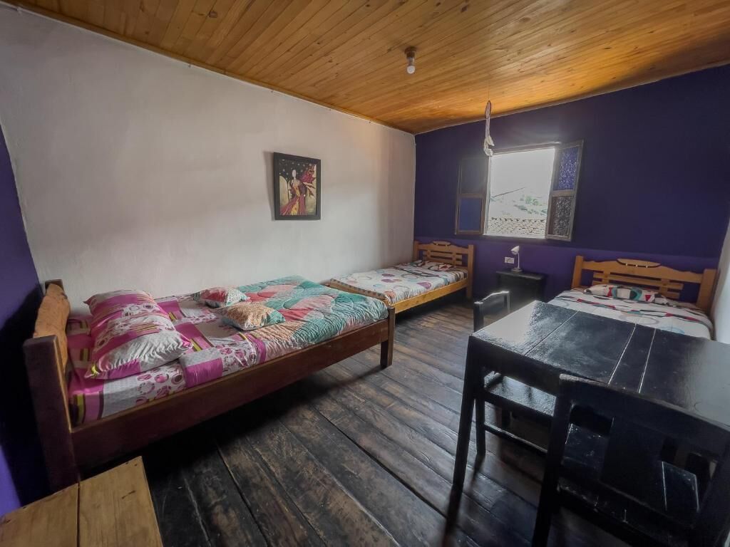 A room with two wooden beds, a dining table, and a window with a view.