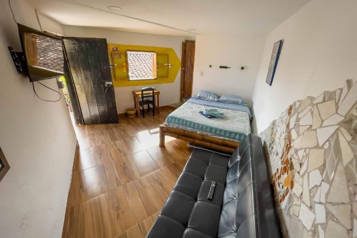 A bedroom with a bed, a bench, a desk, and a window.