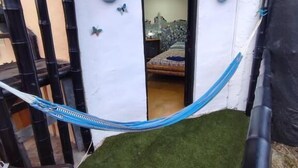 Ein Zimmer mit einer Hängematte, einem Bett und einer kleinen Tür zu einem anderen Raum.
