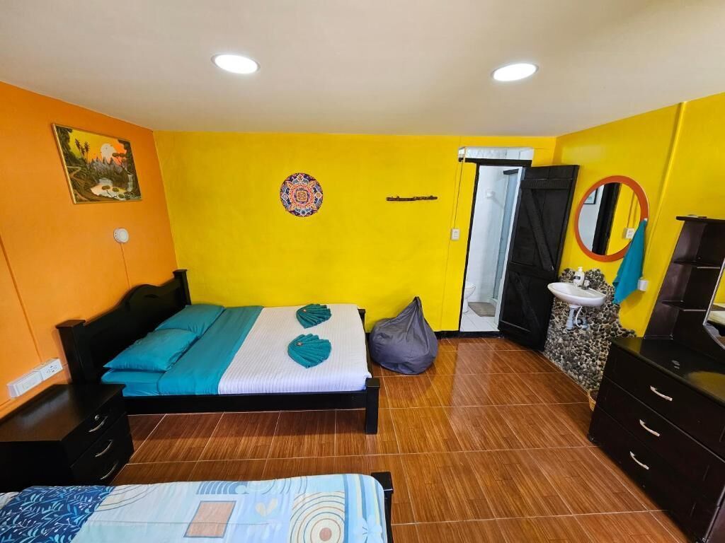 Een kamer met een bed, bureau, stoel, wastafel en spiegel.