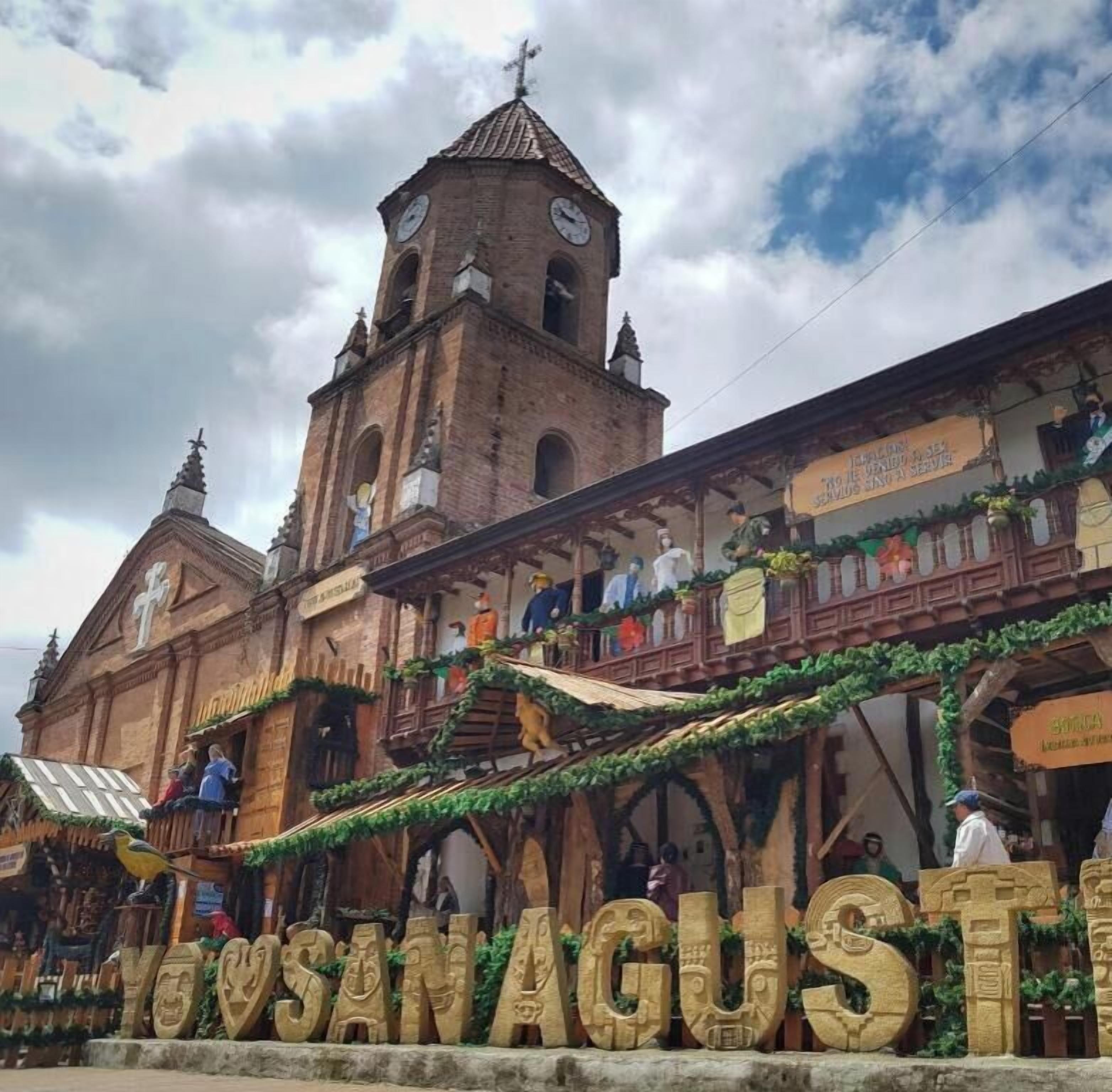 A historic building with a clock tower, a covered walkway with people, and a sign reading 'YOSANAGUSTA'.
