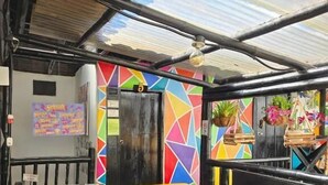 Ein Restaurant mit farbenfrohem geometrischen Wanddesign, einer schwarzen Tür und einem Tisch mit roter und blauer Tischdecke.