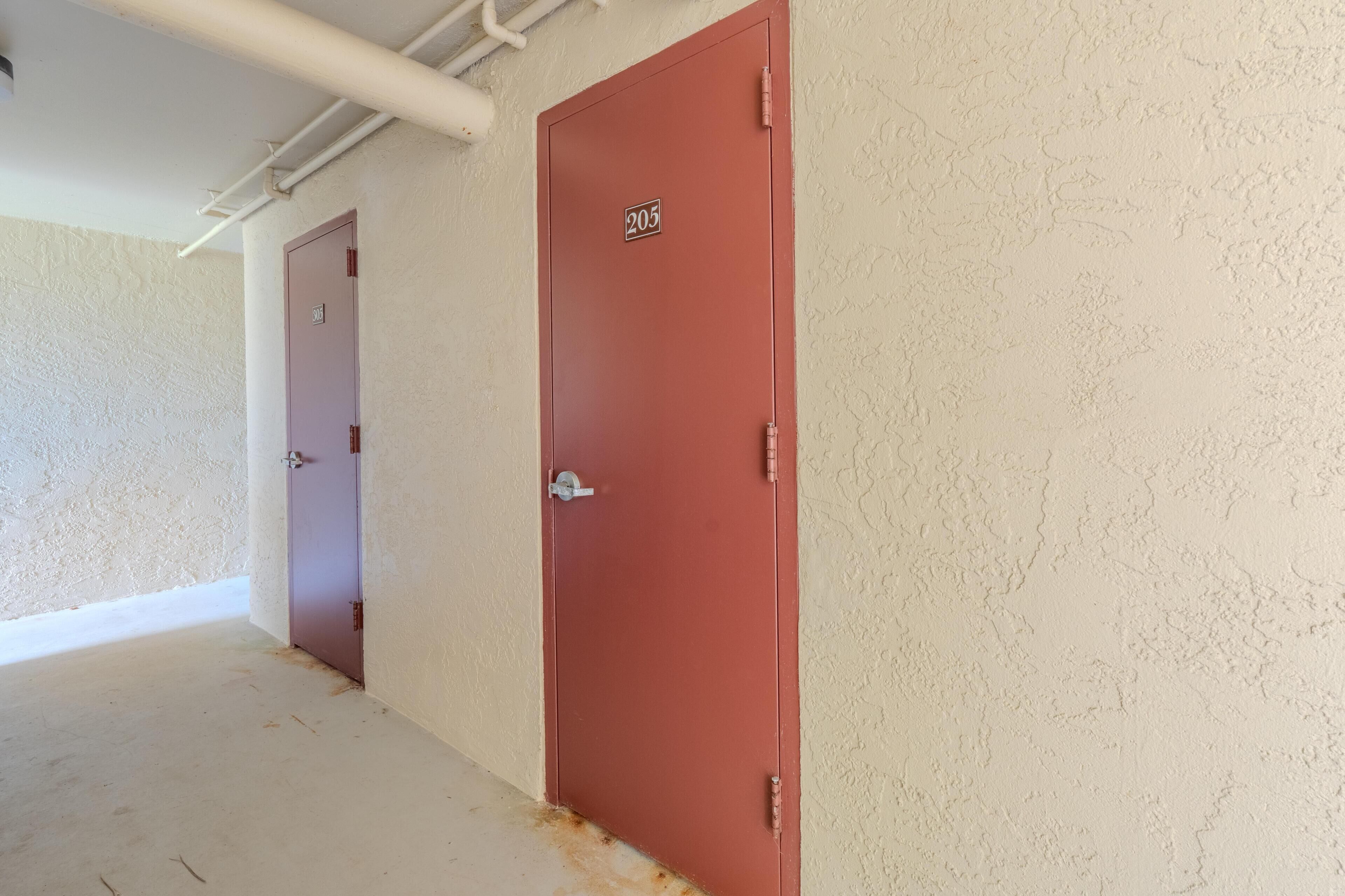 Un couloir avec une porte rouge portant le numéro « 205 » et une porte violette.