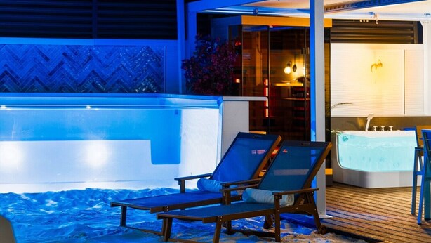 Een buitenpool met verwarming, ligbedden en een jacuzzi.