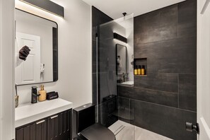 A modern bathroom with a large mirror, a vanity with a towel, and a shower area. - Heated Glass Pool + White Sand | Private Spa (Phoenix)