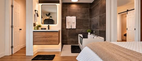 A modern bedroom with a large bed, a built-in wardrobe, a vanity with a mirror, and a shower area.