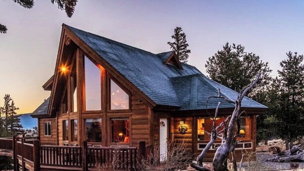 A log cabin with a large front porch, a prominent chimney, and a view of the surrounding landscape. - Luxury Off-Grid Mountain Cabin on 4 Acres, Views, Serenity and Wellness (Jefferson)