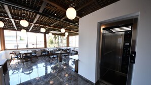 Un interior moderno con suelo de mármol, mesas de madera y lámparas colgantes.