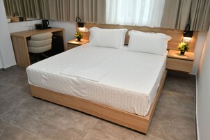 A hotel room with a large bed, a desk, and two bedside tables with lamps.