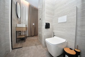 Un baño moderno con cabina de ducha de vidrio, un lavabo blanco y un inodoro.