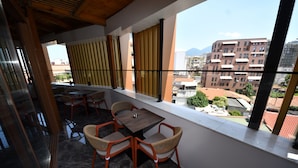 Un balcón con mesa y sillas, vistas a edificios y techo de madera.