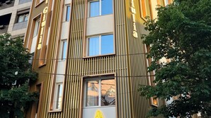 Un moderno edificio de hotel con diseño vertical, amplias ventanas y un logotipo destacado.