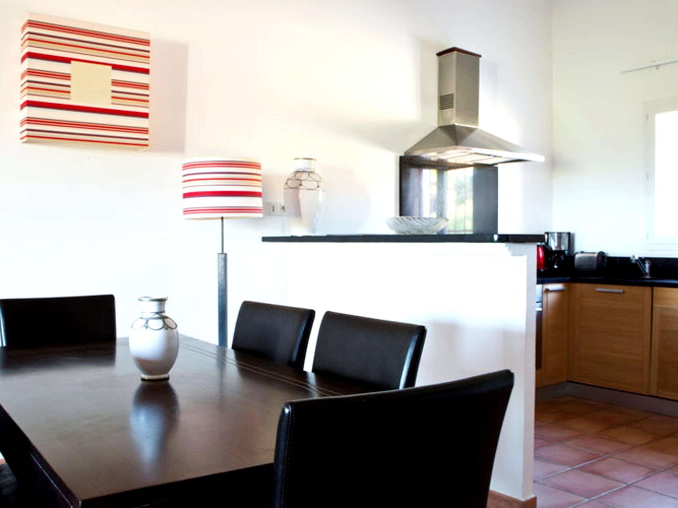 Een moderne keuken met een eettafel, stoelen, een fornuis en een raam.