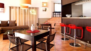 A modern kitchen with a dining area, red bar stools, and a staircase leading to an upper level. - Golf-side Holiday Home in Mazamet (Roquebrune-sur-Argens)