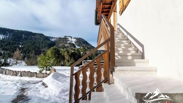 A staircase leading to a building with a view of snow-covered mountains. - Appt expo Sud 75 m2 - 1 séance SPA & Sauna - 3 Ch. (La Clusaz)