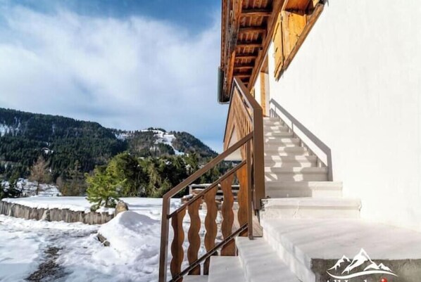 A staircase leading to a building with a view of snow-covered mountains. - Appt expo Sud 75 m2 - 1 séance SPA & Sauna - 3 Ch. (La Clusaz)
