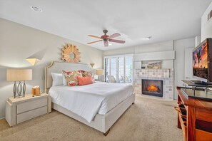 A bedroom with a bed, nightstand, lamp, ceiling fan, fireplace, and a TV. - SRC301 Cozy 3BR Santa Rosa Cove Condo near Pool (La Quinta)
